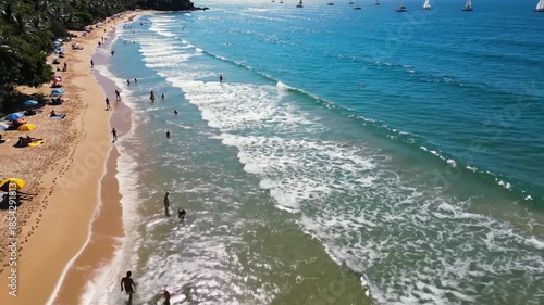 Aerial view of a beautiful beach with people enjoying the ocean and water sports.