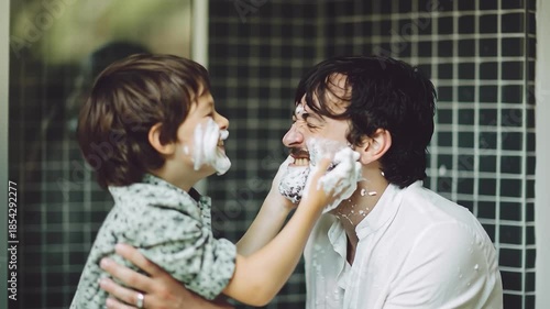 Happy child playing with shaving cream on father's face
