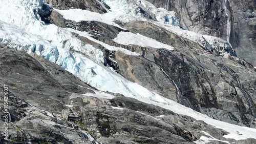 Norwegian Glacier Melting on Rocky Mountainside During Warm Sunny Day in Summer