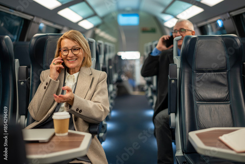Cuadro en lienzo Smiling mature woman discussing on smartphone during train journey