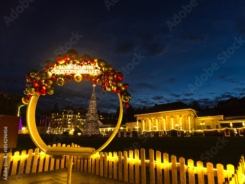 Festive Christmas Baden-Baden arch stand for touristic selfies with ornaments and lights overlooking illuminated casino and Christmas market at dusk