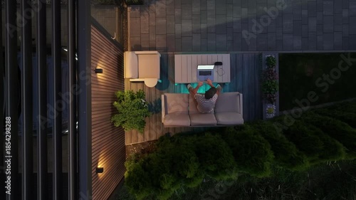 Working on a Laptop in a Backyard Next to Modern Carport