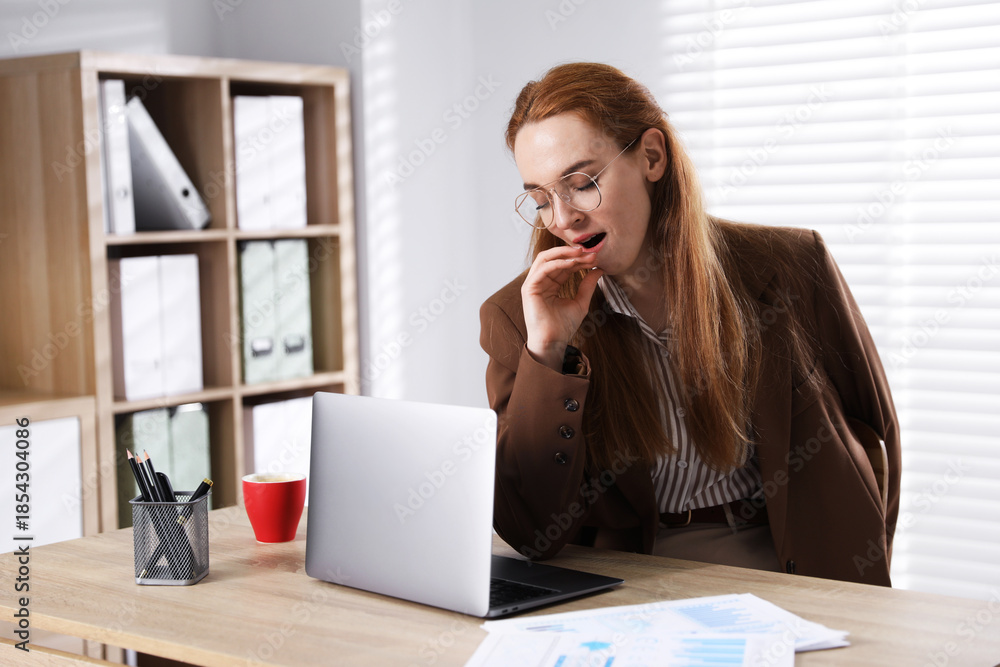 Obraz premium Sleepy woman yawning at workplace in office