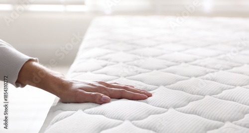 Tableau sur toile Woman touching soft mattress on bed indoors, closeup