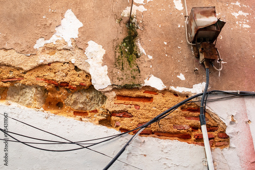 Weathered Urban Wall with Exposed Wires and Crumbling Plaster