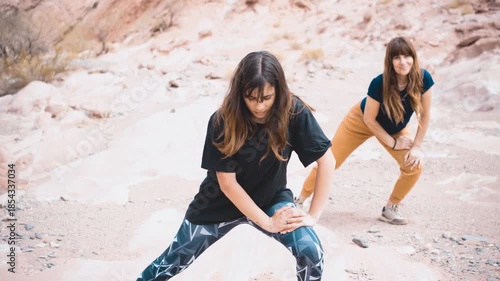 Young Caucasian women stretching in a rocky desert landscape, warming up in casual active-wear