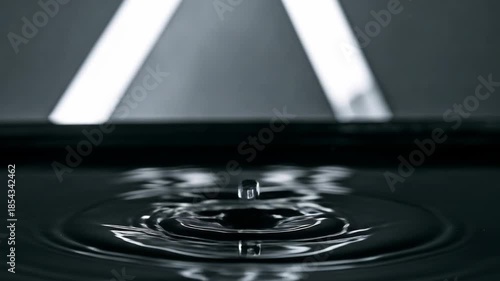 A captivating macro shot of a water droplet creating ripples in dark liquid.
