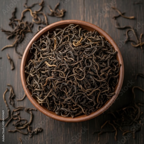 Aromatic black tea leaves in rustic bowl on aged wood surface creating mood