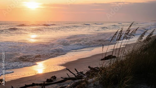 Golden Hour Ocean Waves Crash On Sandy Beach With Sea Oats Under A Warm Sunset Sky