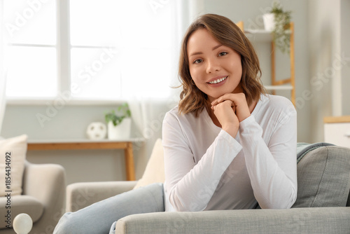 Beautiful young woman with short curly hair sitting on sofa at home Free Download Beautiful young woman with short curly hair sitting on sofa at home - GFXLoad