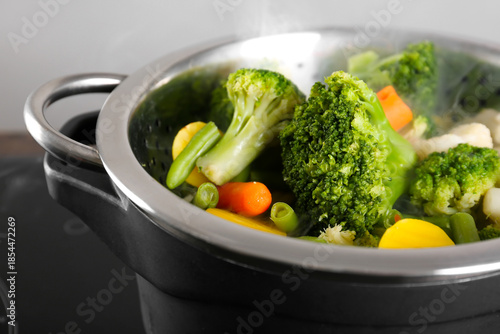 Canvas Print Mixed vegetables steaming in metal colander over pot on stove