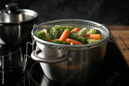 Photography Mixed vegetables steaming in metal colander over pot on stove