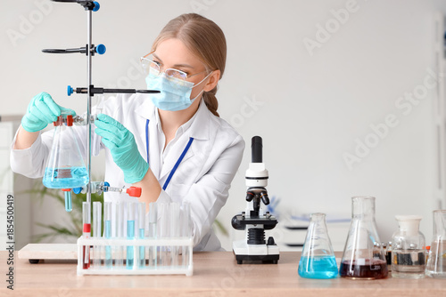 Female scientist with flask and microscope working in laboratory