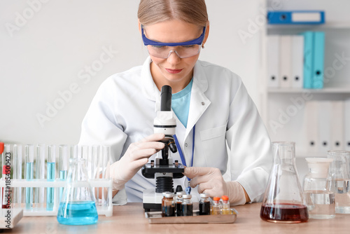 Female scientist with safety goggles and microscope working in laboratory