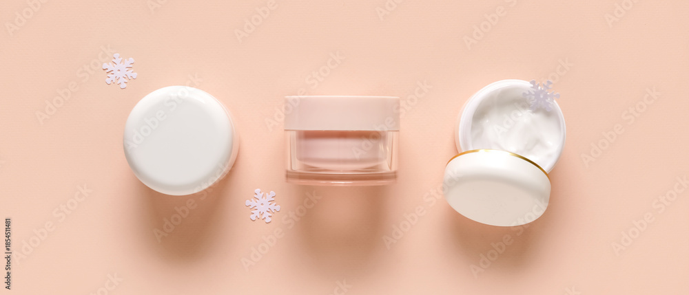Fototapeta premium Jars of cream with snowflakes on pale orange background