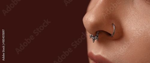 Young woman with nose piercing on dark background with space for text, closeup