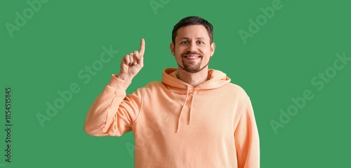 Happy man pointing upward on green background