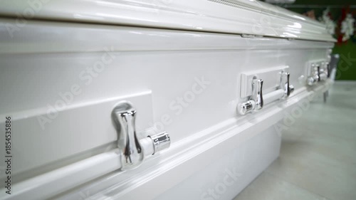 An expensive white glossy coffin is in the store. Funeral and farewell to the deceased.