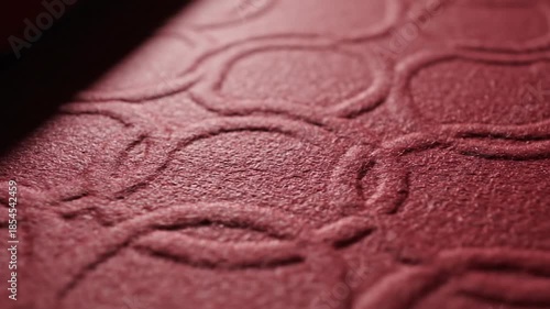 Close-up textural exploration of embossed crimson material surface with dynamic lighting