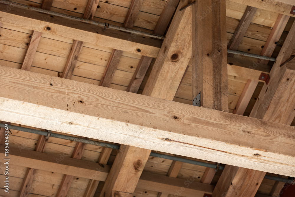 Ταπετσαρία A close view of heavy timber beams and roof framing in a building under construc