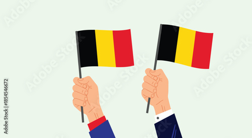 Hands holding two flags of Belgium representing national pride, celebration, and patriotic events during public holidays or festivals.