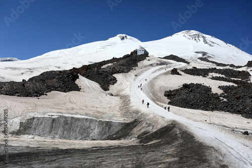 Mount Elbrus tour with people walking up snowy path toward mountain hut