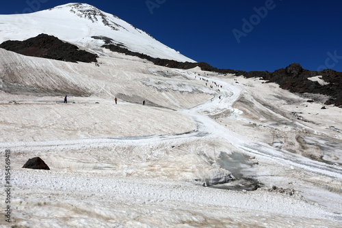 People ascending snowy Mount Elbrus