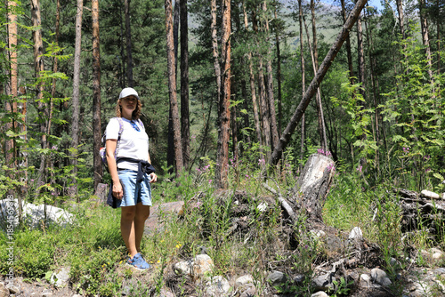 Woman hiker in forest of tall trees and lush green plants