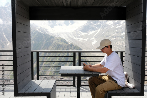 Young man sitting at table in modern mountain view cafe