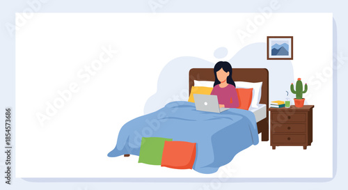 Young woman sitting comfortably in her bed under a blue blanket while working on her laptop computer at night.