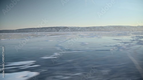 A view from the side window of a vehicle traveling across a frozen lake in the evening. Traveling across a frozen lake