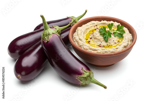 Eggplant beside a bowl of creamy baba ganoush dip garnished with parsley and olive oil