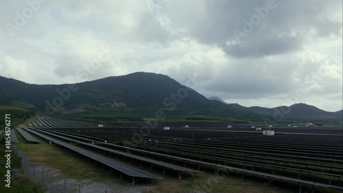 Timelapse reveals rows of solar panels across rolling green hills as clouds race overhead, shifting light and shadow to show scale, motion, and human energy systems. Renewable energy.