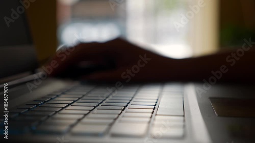 Sitting at a cafe table, a woman types on her laptop with steady concentration, blending productivity and comfort in a relaxed urban workspace. Remote work.