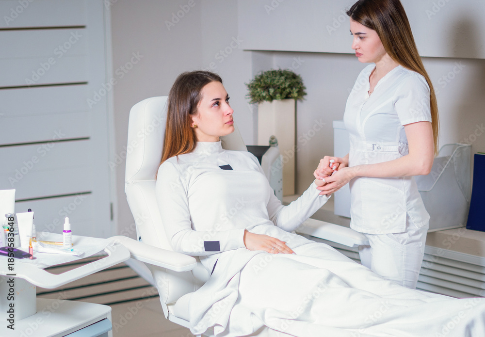 Obraz premium Young pretty woman came to a beauty salon and consults with a beautician on anti-aging treatments.