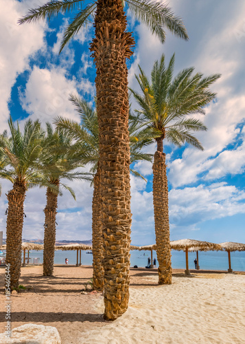 Sunny morning on sandy beach of the Red Sea in Eilat - famous tourist resort and recreational city in Israel