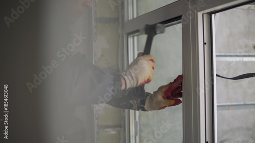 Worker tapping window frame with hammer during installation