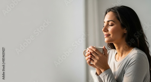 Serene woman with closed eyes enjoying a peaceful moment of self-care with a warm drink.