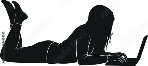 Side view silhouette of a young woman lying on her stomach using a laptop computer for remote work or study.