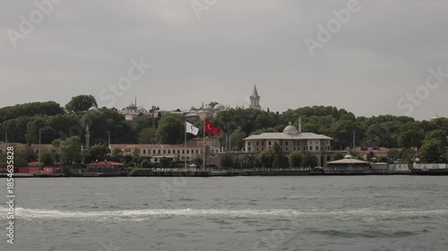 Panoramic view of Istanbul's historic district along the Bosphorus, featuring Ottoman architecture and Turkish flags.
