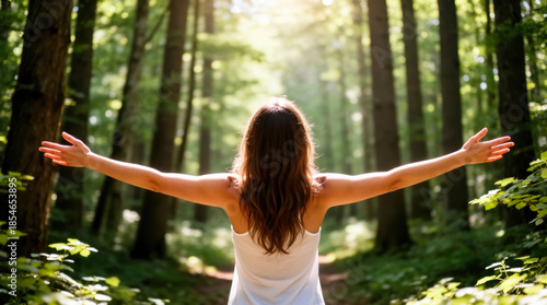 Free Woman Embracing Nature in Sunlit Forest, Back to Camera, Arms Outstretched, Joyful Wellness Lifestyle