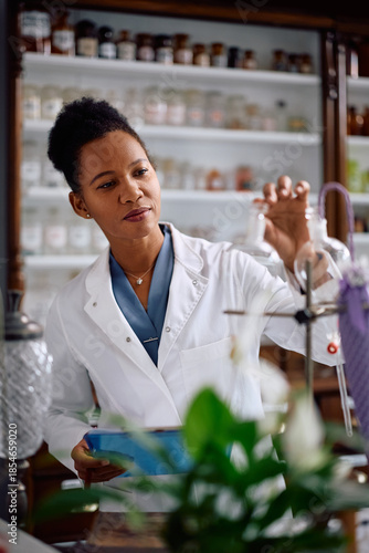 Black female pharmaceutical researcher working in drugstore.