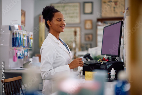 Happy black female pharmacist working in drugstore.