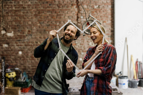 Couple smiling and planning renovation with measuring tape at construction site