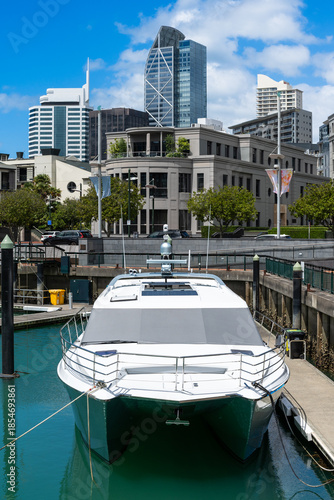 Luxury yachts and motorboats dock at the vibrant Viaduct Harbour with the Auckland skyline and modern CBD architecture in the background.