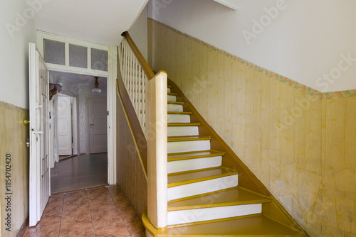 Old fashioned wooden staircase with white rails in hallway