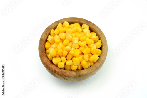 Sweet corn kernels in wooden bowl over white. Cooked canned yellow vegetable maize, Zea mays, also called sugar or pole corn, a vegetarian staple food. Isolated macro food photo close up from above. 
