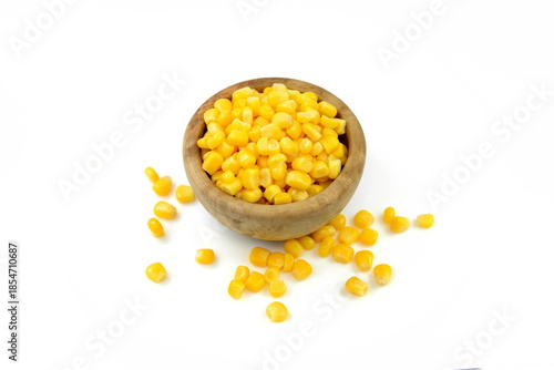 Sweet corn kernels in wooden bowl over white. Cooked canned yellow vegetable maize, Zea mays, also called sugar or pole corn, a vegetarian staple food. Isolated macro food photo close up from above. 