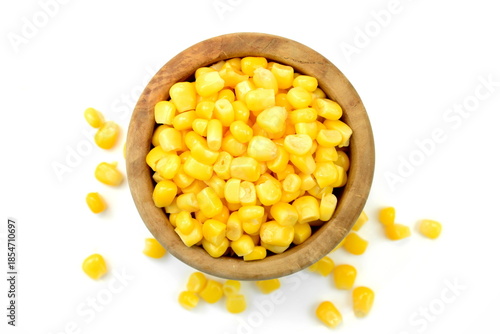 Sweet corn kernels in wooden bowl over white. Cooked canned yellow vegetable maize, Zea mays, also called sugar or pole corn, a vegetarian staple food. Isolated macro food photo close up from above. 
