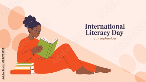 A young woman wearing orange reclines on the floor reading an open book for International Literacy Day celebration